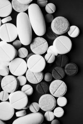 black, white and grey tablets and pills on dark background