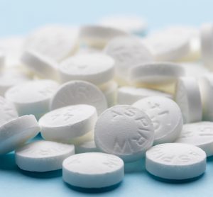 White aspirin pills on blue paper background.