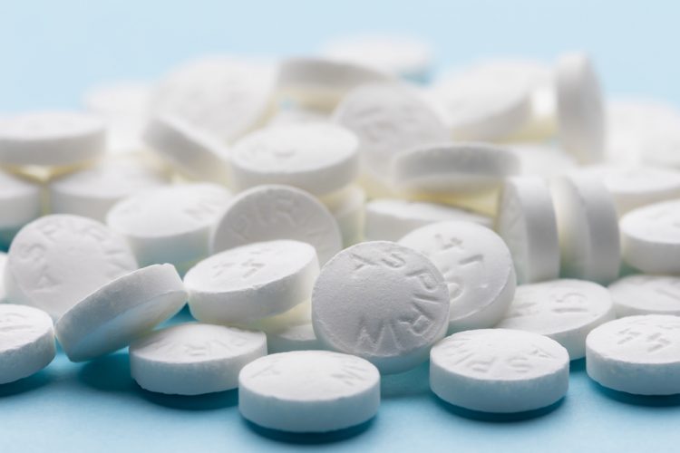 White aspirin pills on blue paper background.