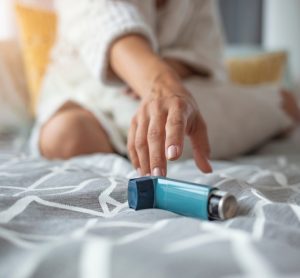 Young woman reaching for her blue inhaler