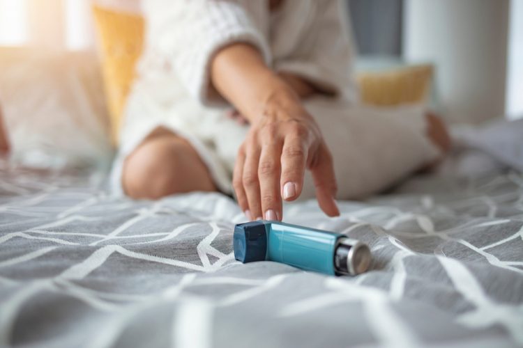 Young woman reaching for her blue inhaler