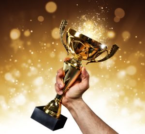 an holding up a gold trophy cup with abstract shiny background