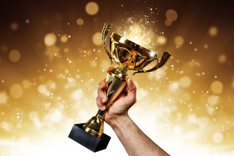 an holding up a gold trophy cup with abstract shiny background
