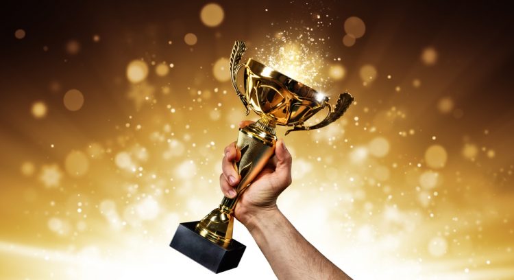 an holding up a gold trophy cup with abstract shiny background