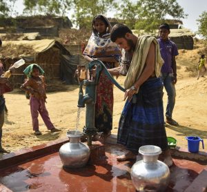 people using a pump to draw water out a tap