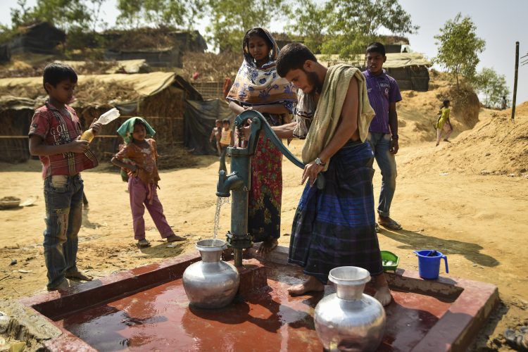 people using a pump to draw water out a tap