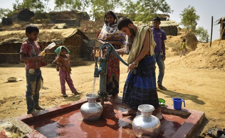 people using a pump to draw water out a tap