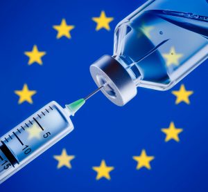 syringe drawing from a vial in front of the EU flag (blue with a central circle of golden stars) - vaccines are an example of biopharmaceuticals