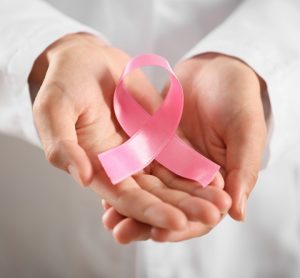 Doctor in white coat holding pink ribbon - symbol of breast cancer