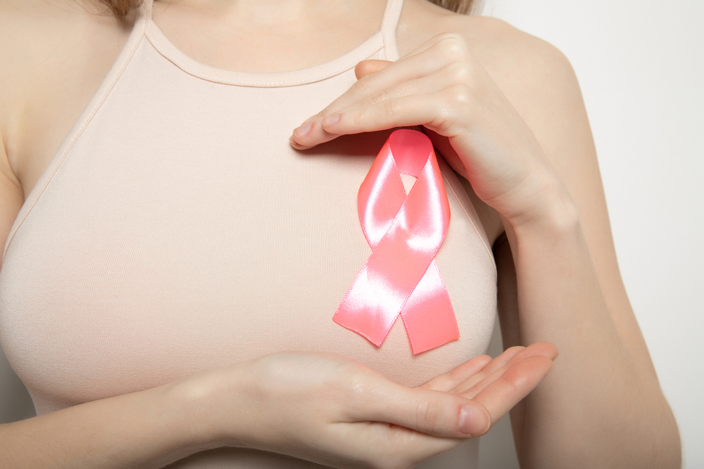 Pink ribbon on the girl’s chest - breast cancer