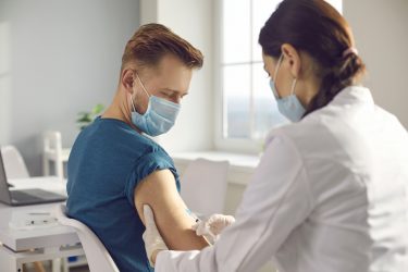 idea of clinical trials - Man in medical face mask getting injection at hospital.