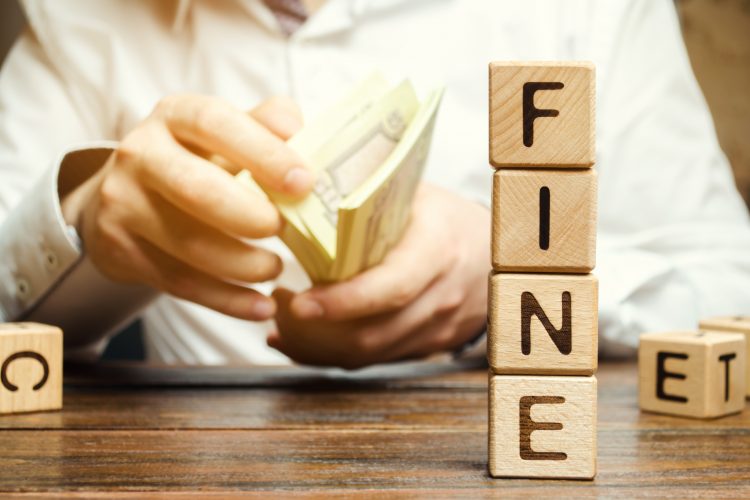 man holding a wad of paper money notes with 'fine' spelt in blocks next to him