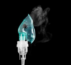 oxygen mask with vapour coming out of it on a black background - idea of inhaled therapies