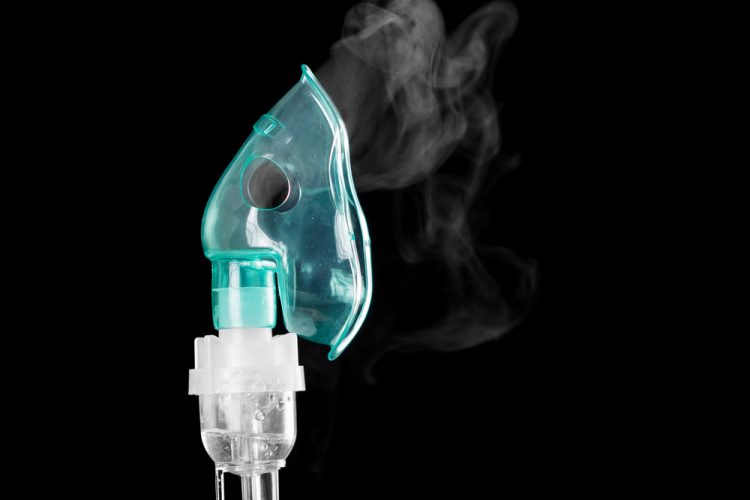 oxygen mask with vapour coming out of it on a black background - idea of inhaled therapies