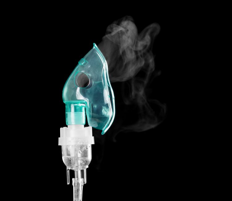 oxygen mask with vapour coming out of it on a black background - idea of inhaled therapies