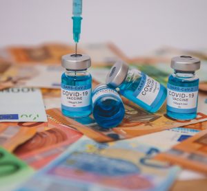 Vials labelled 'COVID-19 Vaccine' on a pile of bank notes