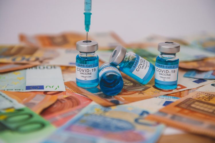 Vials labelled 'COVID-19 Vaccine' on a pile of bank notes