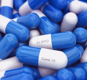 Blue and white capsules labelled 'COVID-19' - idea of tablet COVID-19 vaccine