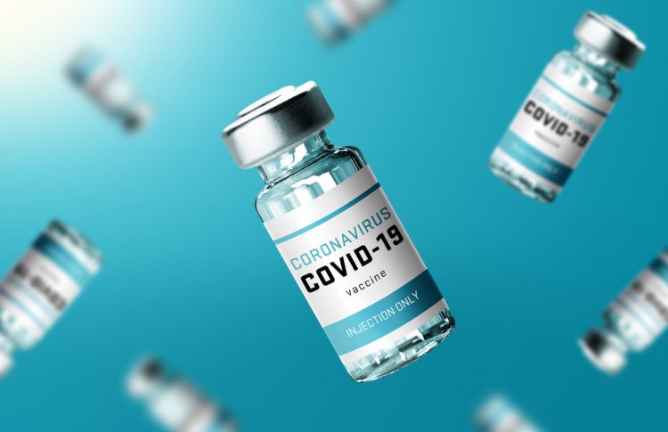 Glass vials labelled 'COVID-19 CORONAVIRUS VACCINE' falling in front of a turquoise background'