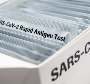 Box with a series of silver packages in - one pulled out is labelled 'SARS-CoV-2 RAPID ANTIGEN TEST'