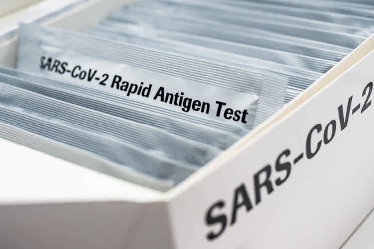 Box with a series of silver packages in - one pulled out is labelled 'SARS-CoV-2 RAPID ANTIGEN TEST'