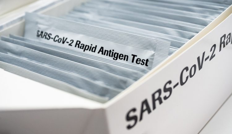 Box with a series of silver packages in - one pulled out is labelled 'SARS-CoV-2 RAPID ANTIGEN TEST'
