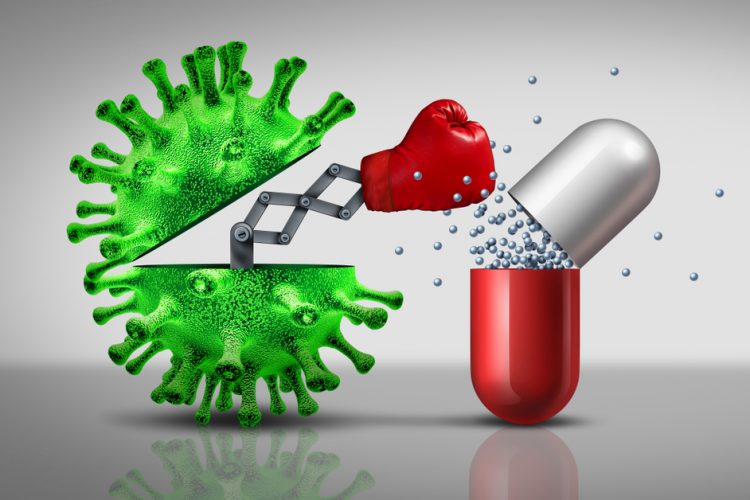 green coronavirus particle punching a medicine capsule (red and white) - idea of coronavirus not affected by antibiotics