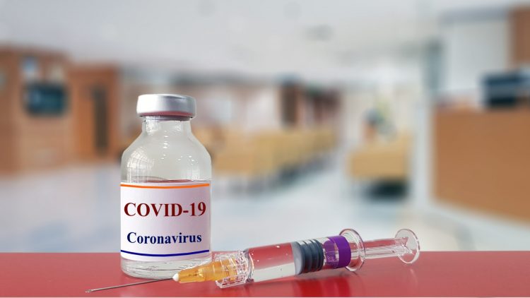 vial of liquid labelled 'COVID-19 coronavirus' with a syringe on a blurred background