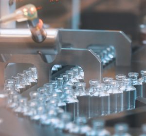 vials filled with clear liquid on a production line - idea of COVID-19 vaccine manufacturing