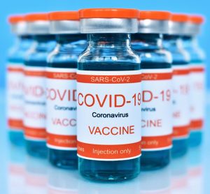 Vials labelled with 'COVID-19 Vaccine' on a blue table