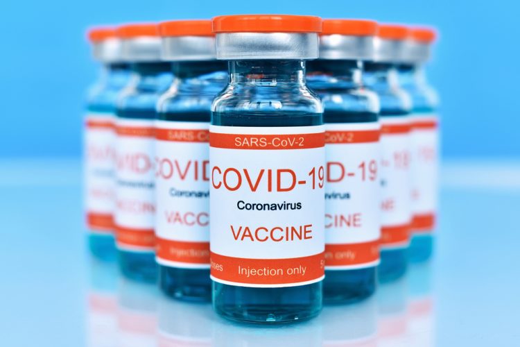 Vials labelled with 'COVID-19 Vaccine' on a blue table