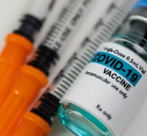 syringes next to a vial labelled 'COVID-19 VACCINE'
