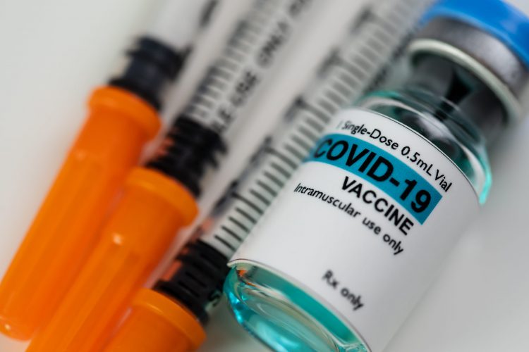 syringes next to a vial labelled 'COVID-19 VACCINE'