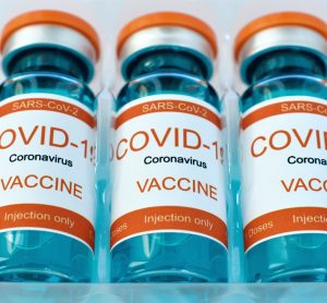 Row of vials labelled 'COVID-19 Coronavirus Vaccine' in plastic packaging