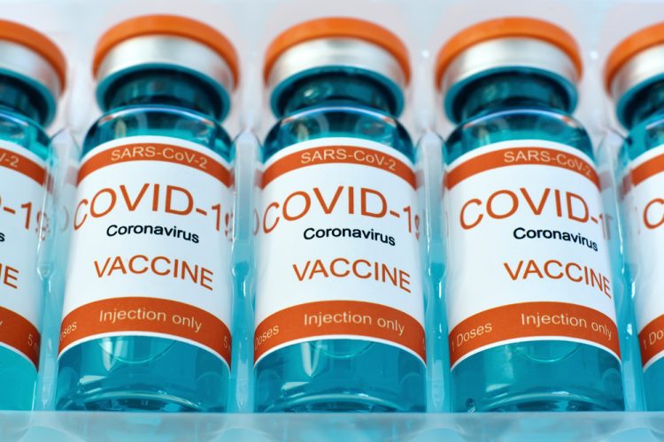 Row of vials labelled 'COVID-19 Coronavirus Vaccine' in plastic packaging