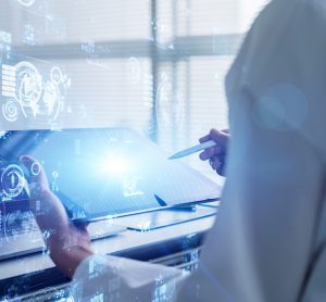 person in white lab coat operating a tablet