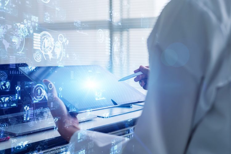 person in white lab coat operating a tablet