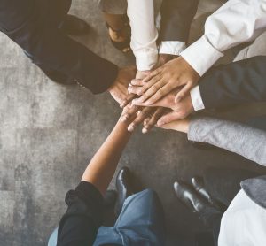 close up of the hands of a group of business people piled together in the middle of a circle - idea of collaboration