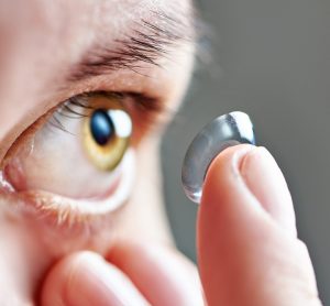 Close up of a person bringing a contact lens close to their eye