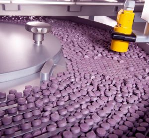 tablet conveyor filled with purple tablets - idea of pharmaceutical manufacturing