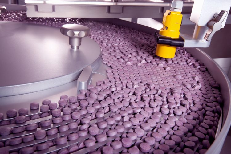 tablet conveyor filled with purple tablets - idea of pharmaceutical manufacturing