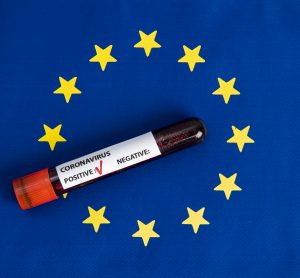 European Union flag (blue with circle of gold stars) with a blood vial on top labelled 'Coronavirus test, positive'