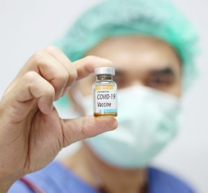 doctor holding vial labelled 'COVID-19 Coronavirus vaccine'