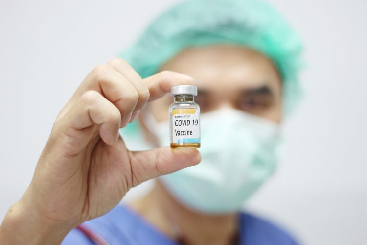doctor holding vial labelled 'COVID-19 Coronavirus vaccine'