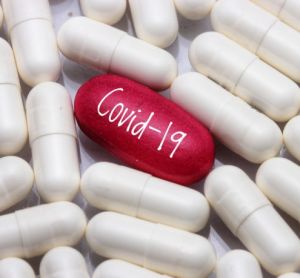 Covid-19 treatment concept - red pill labelled COVID-19 surrounded by blank white capsules