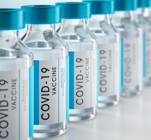 3D illustration of vials labelled 'COVID-19 Vaccine' in a row