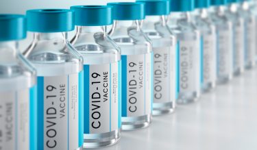 3D illustration of vials labelled 'COVID-19 Vaccine' in a row