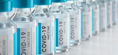 3D illustration of vials labelled 'COVID-19 Vaccine' in a row