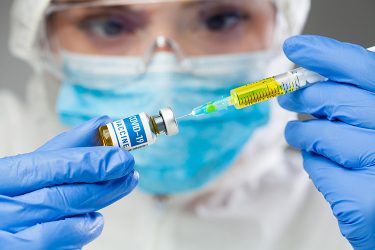 Female doctor drawing a dose of COVID-19 vaccine into a syringe