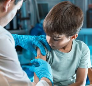 Young male child recieving an injection from a doctor in his upper arm